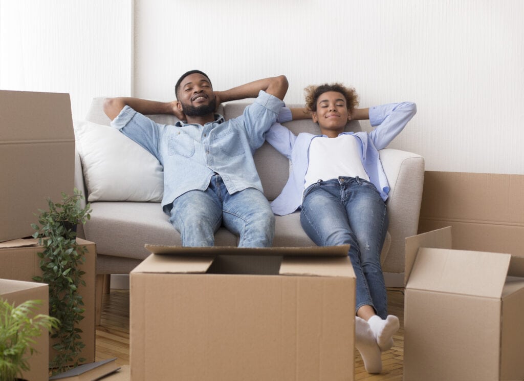 african american spouses relaxing sitting on couch in new apartment
